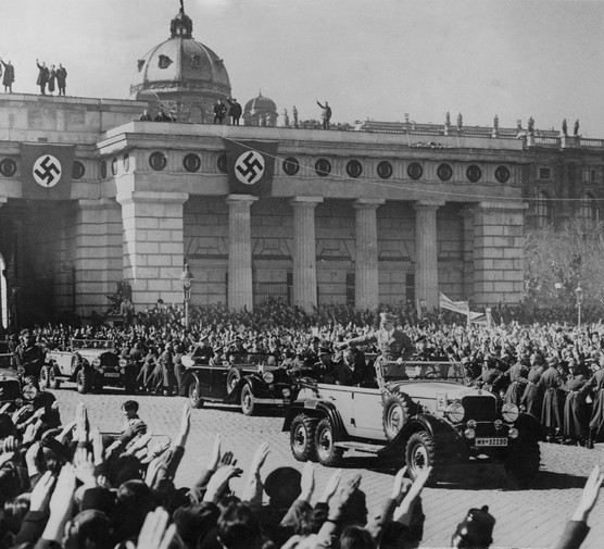 Adolf Hitler – at the time chancellor of Austria – is saluted by the crowds as he makes his way to the great parade of troops in Vienna, Austria, March 1938. (Photo by Keystone/Hulton Archive/Getty Images)