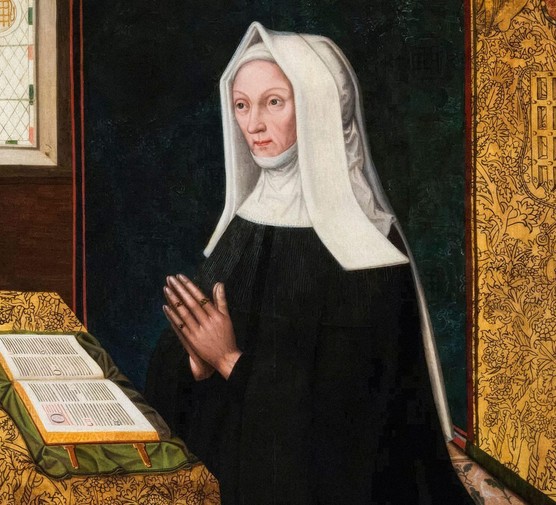 A woman wearing a black dress and white hood, praying in front of a Bible