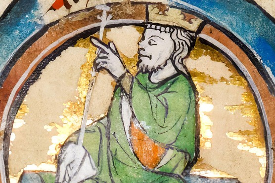 An illustration of a king dressed in a green and orange robe. He is wearing a crown and holding a sceptre