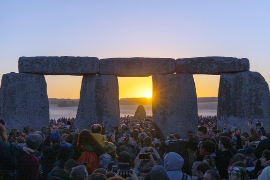 Crowds gather to watch the summer solstice sunrise at the ancient stone circle of Stonehenge, 2019