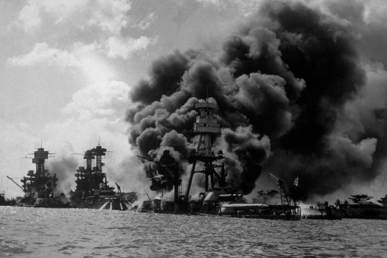The USS Arizona burning in Pearl Harbor following the Japanese attack. To the left of her are USS Tennessee and the sunken USS West Virginia. (Photo by Hulton Archive/Getty Images)