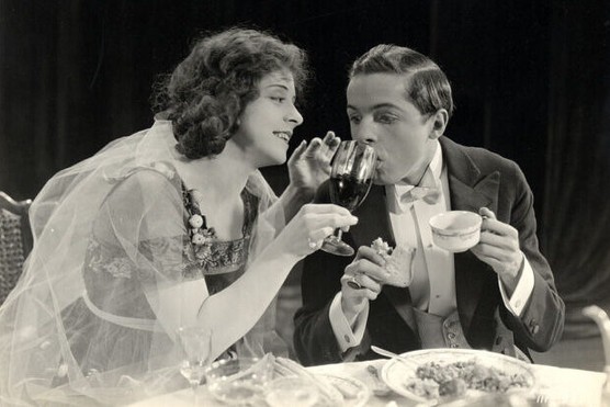 American actress Ethel Grandin (1894 - 1988) holds a wine glass for a man in a tuxedo in a still from an unidentified silent film, circa 1920. (Photo by Vintage Images/Getty Images)