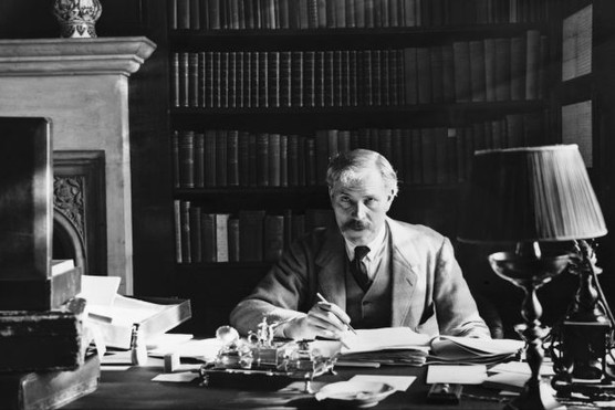 Former British prime minister Ramsay MacDonald sitting behind a desk