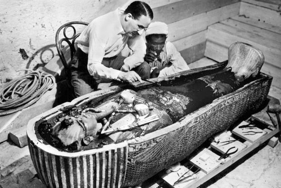 Egyptologist Howard Carter crouches near the golden sarcophagus of Tutankhamun's remains